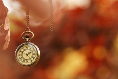 Photo of Autumn time. Chain watch hanging on tree in park, selective focus. Space for text