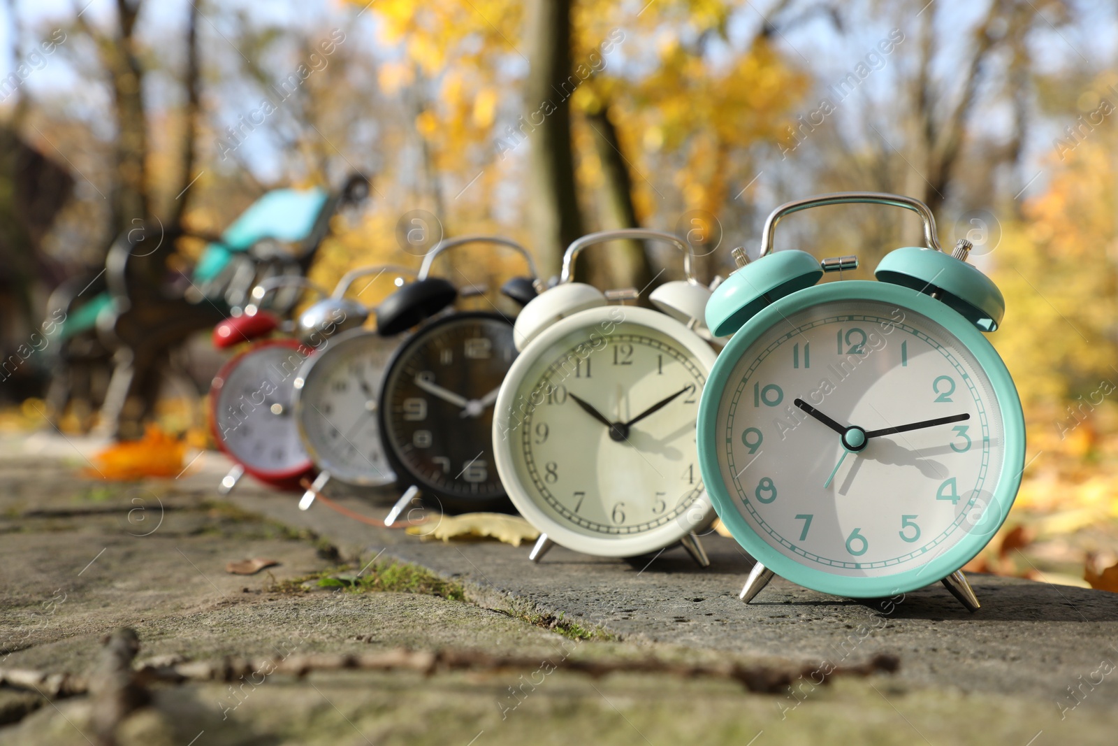 Photo of Alarm clocks on paved pathway in park at autumn