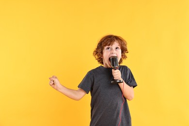 Photo of Little boy with microphone singing on yellow background