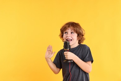 Photo of Little boy with microphone singing on yellow background