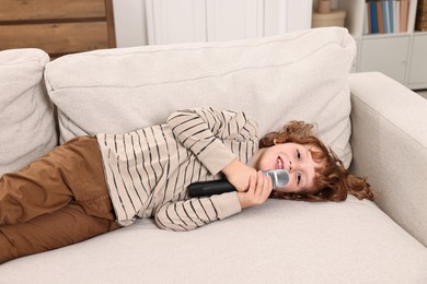 Photo of Little boy with microphone on sofa at home