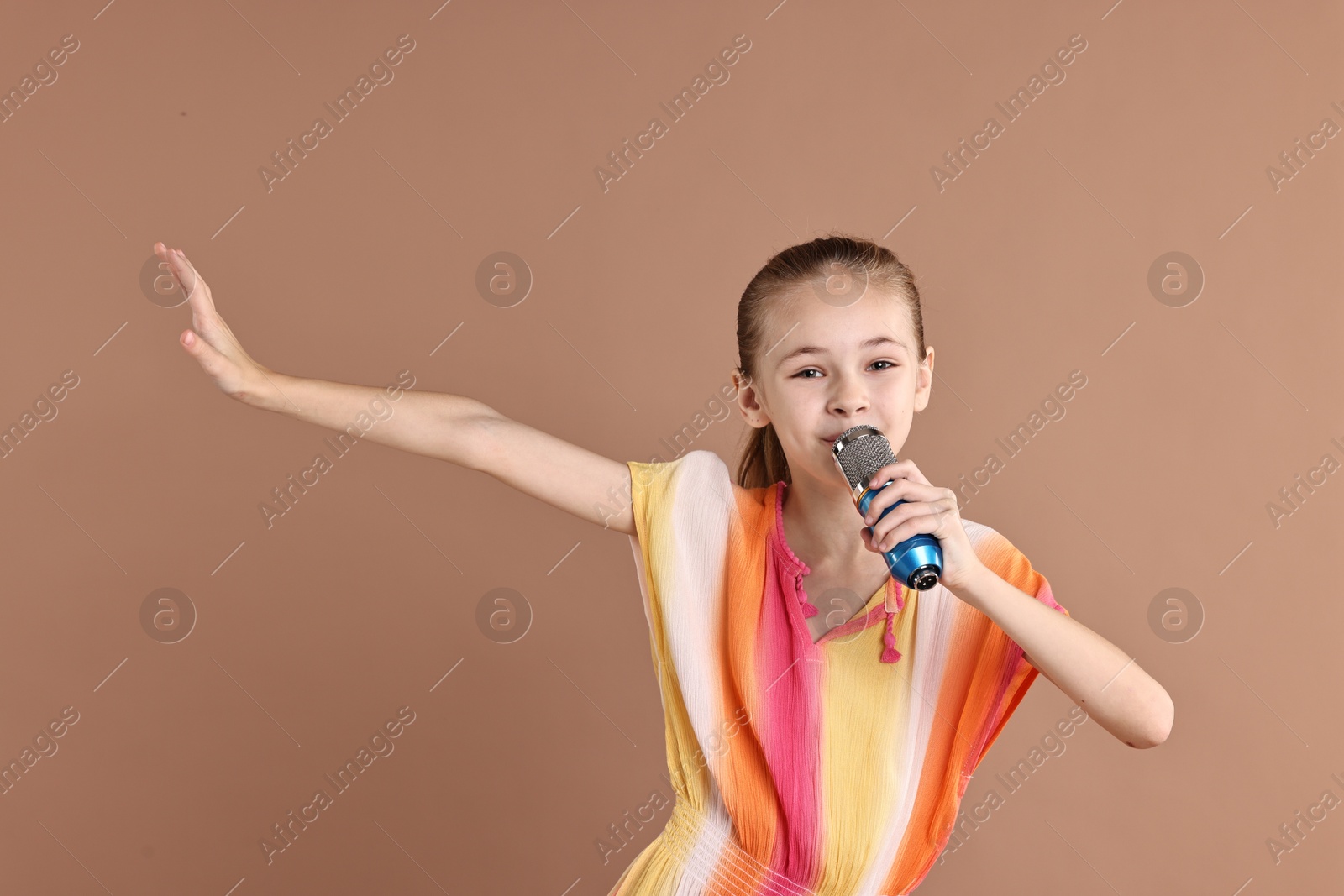 Photo of Little girl with microphone singing on light brown background