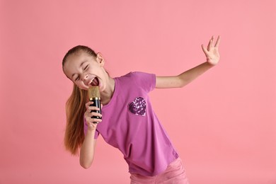 Photo of Little girl with microphone singing on pink background