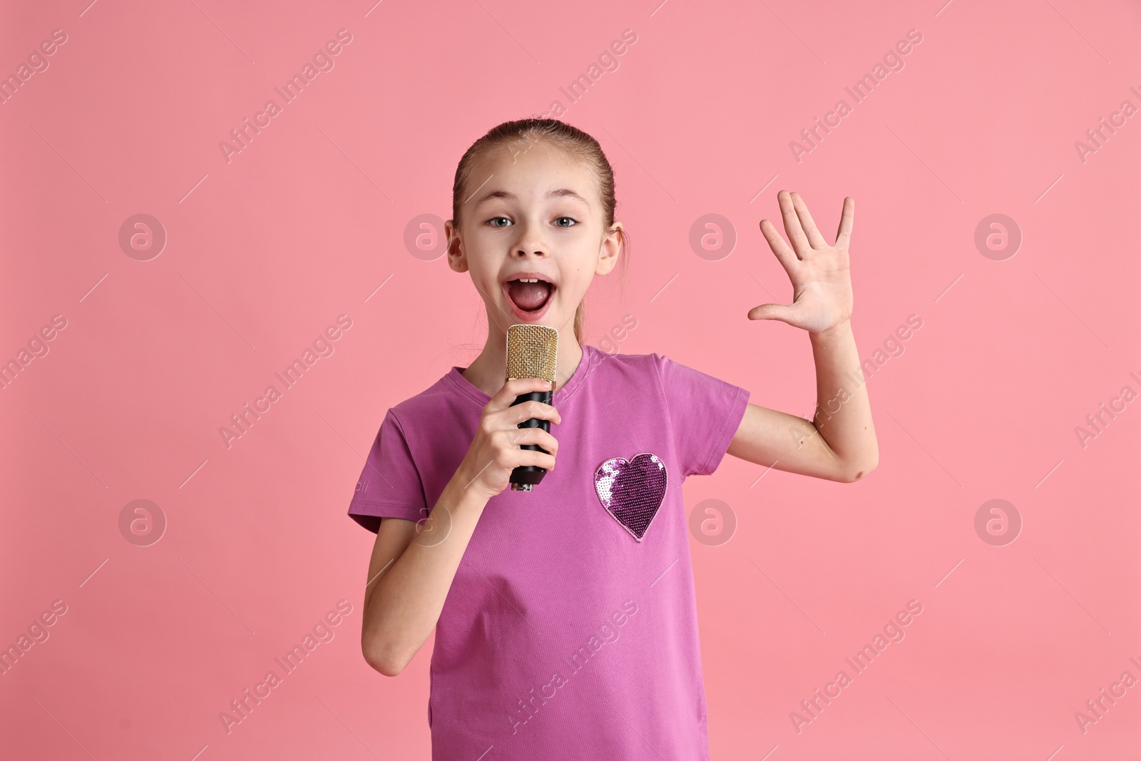 Photo of Little girl with microphone singing on pink background