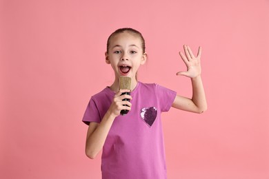 Photo of Little girl with microphone singing on pink background