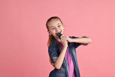 Photo of Little girl with microphone singing on pink background