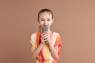 Photo of Little girl with microphone on light brown background