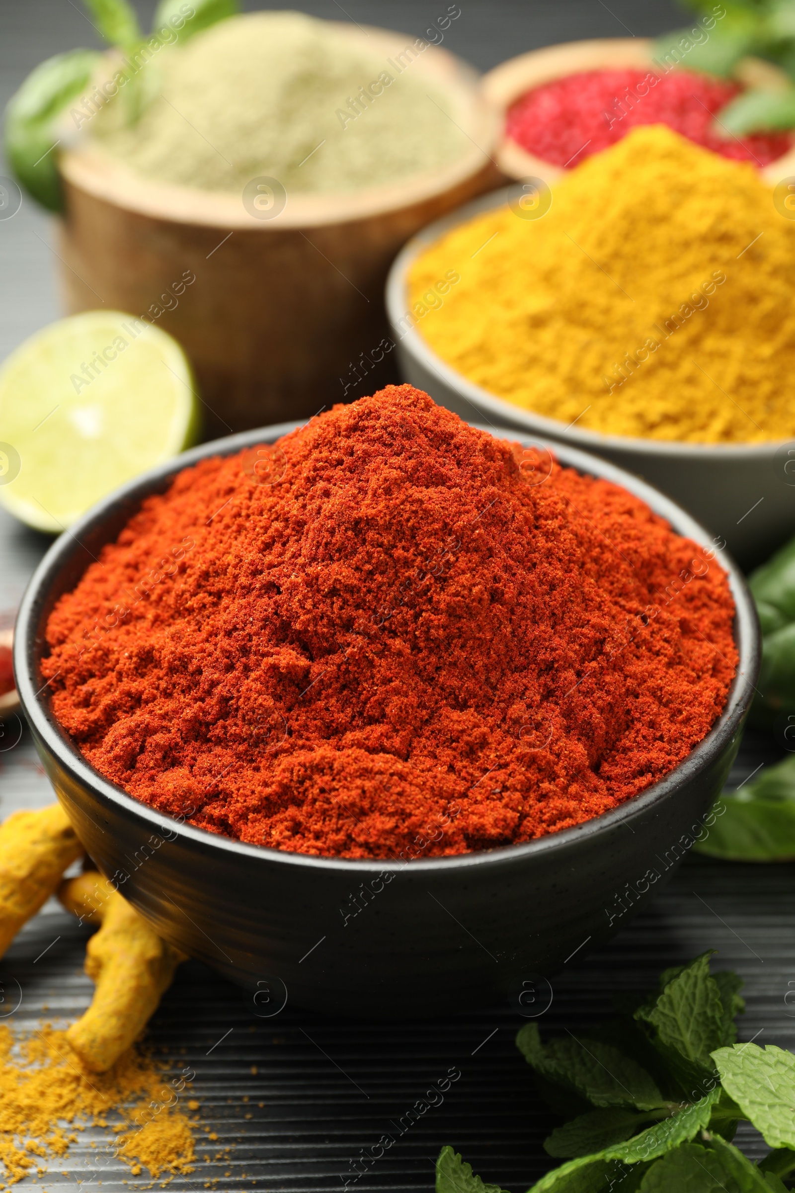 Photo of Different aromatic spices and herbs on black background, closeup