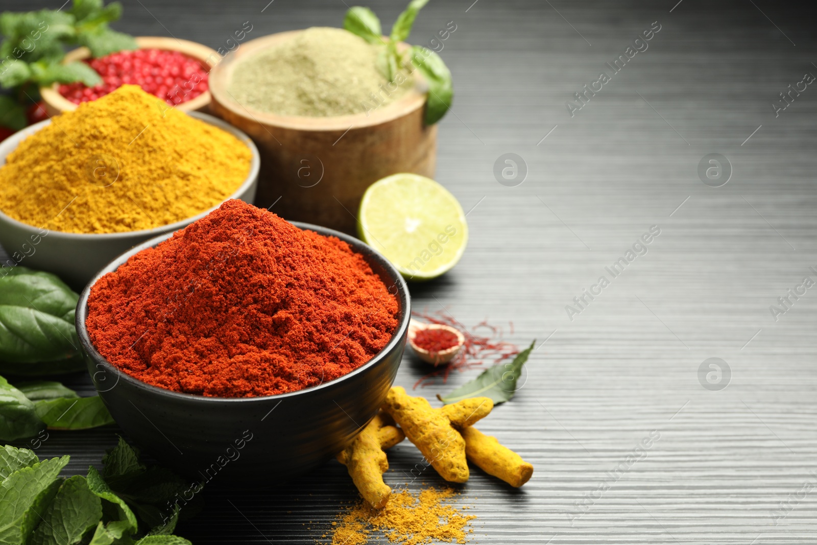 Photo of Different aromatic spices and herbs on black background, closeup