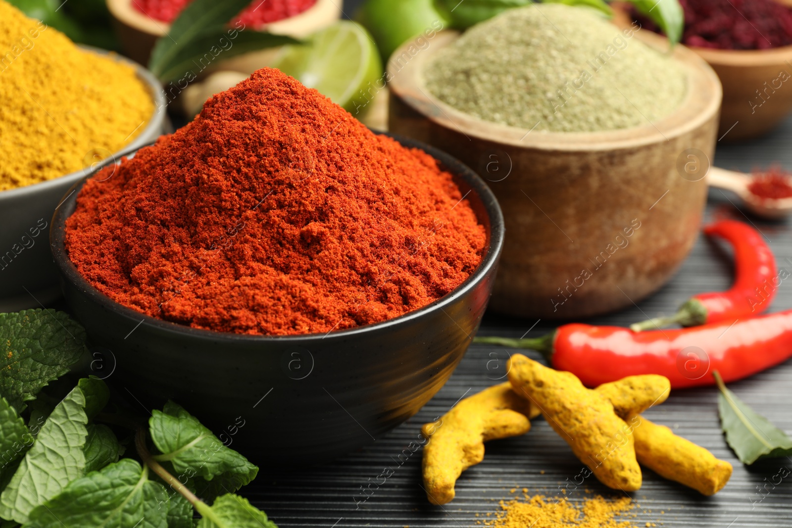 Photo of Different aromatic spices and herbs on black background, closeup