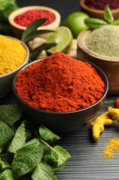 Photo of Different aromatic spices and herbs on black background, closeup