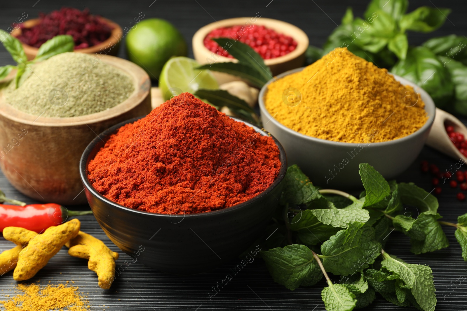 Photo of Different aromatic spices and herbs on black background, closeup