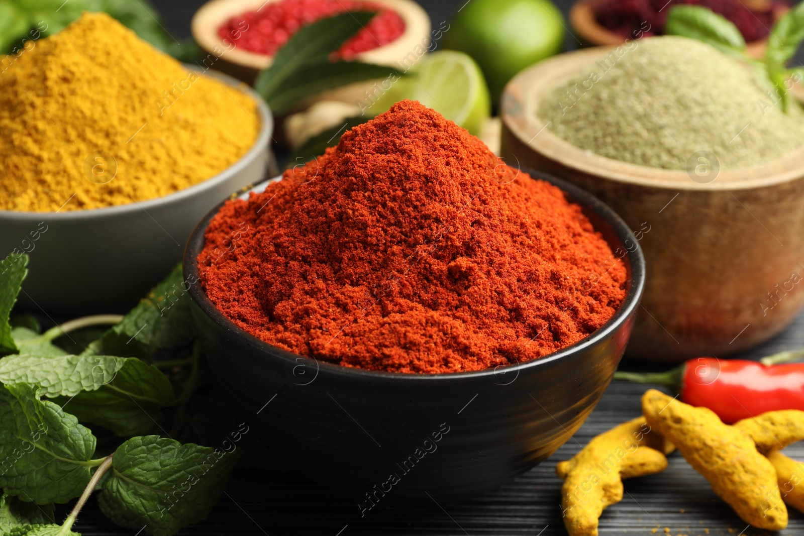 Photo of Different aromatic spices and herbs on black background, closeup