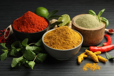 Photo of Different aromatic spices and herbs on black background, closeup