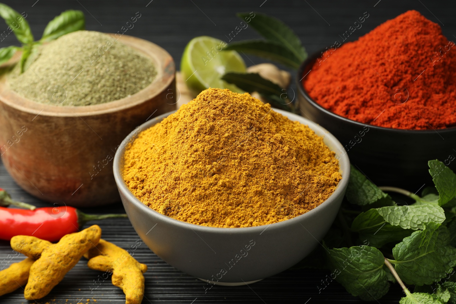 Photo of Different aromatic spices and herbs on black background, closeup