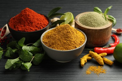 Photo of Different aromatic spices and herbs on black background, closeup