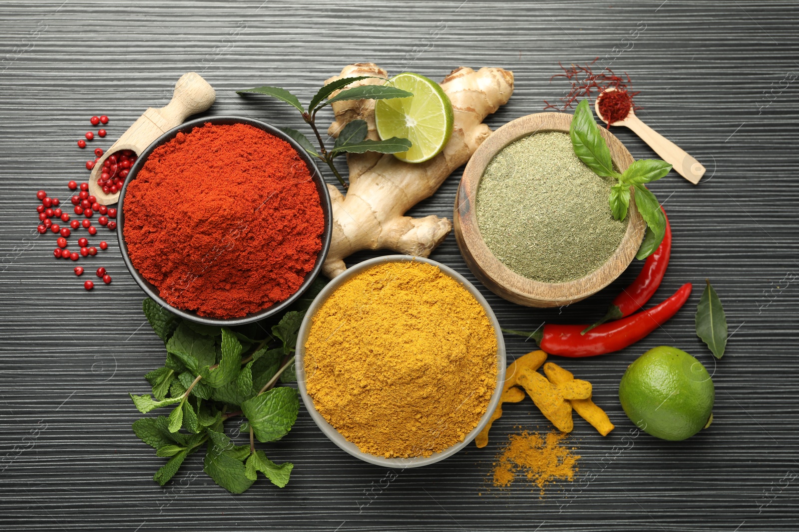 Photo of Different aromatic spices, lime and herbs on black background, flat lay