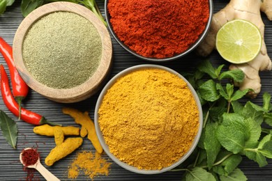 Different aromatic spices, lime and herbs on black background, flat lay