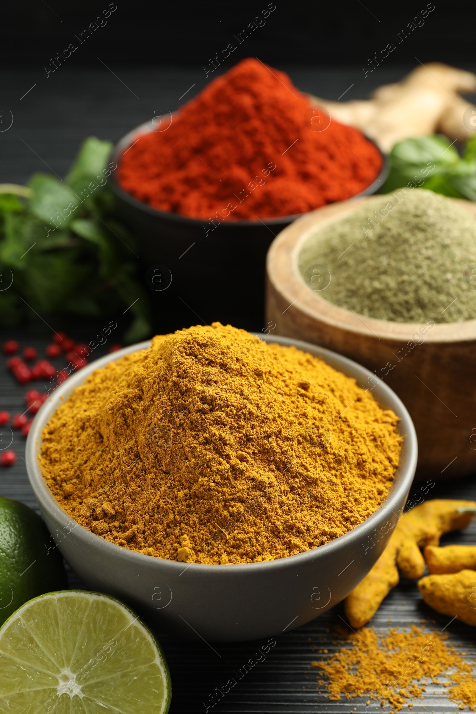 Photo of Different aromatic spices, lime and herbs on black background, closeup