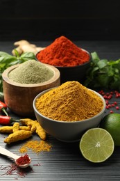 Photo of Different aromatic spices, lime and herbs on black background, closeup