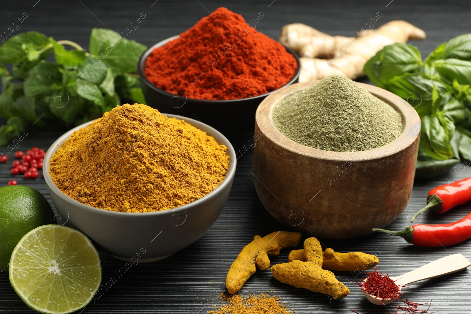 Photo of Different aromatic spices, lime and herbs on black background, closeup