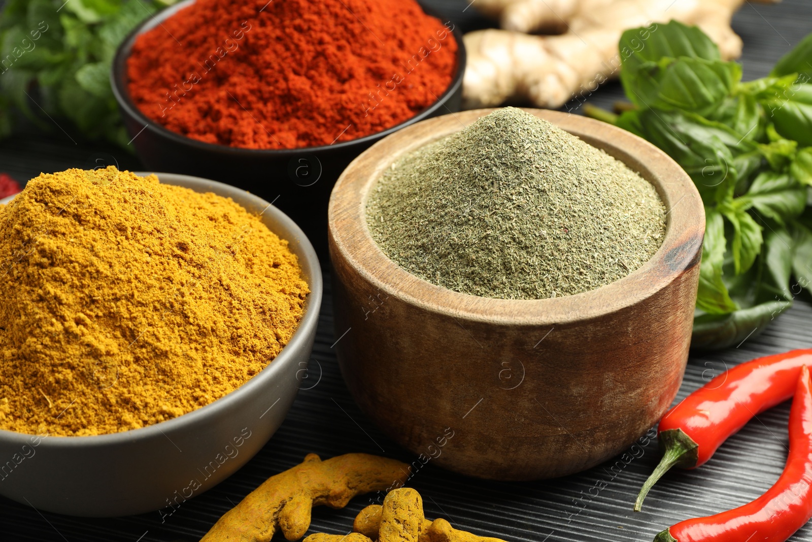 Photo of Different aromatic spices and herbs on black background, closeup