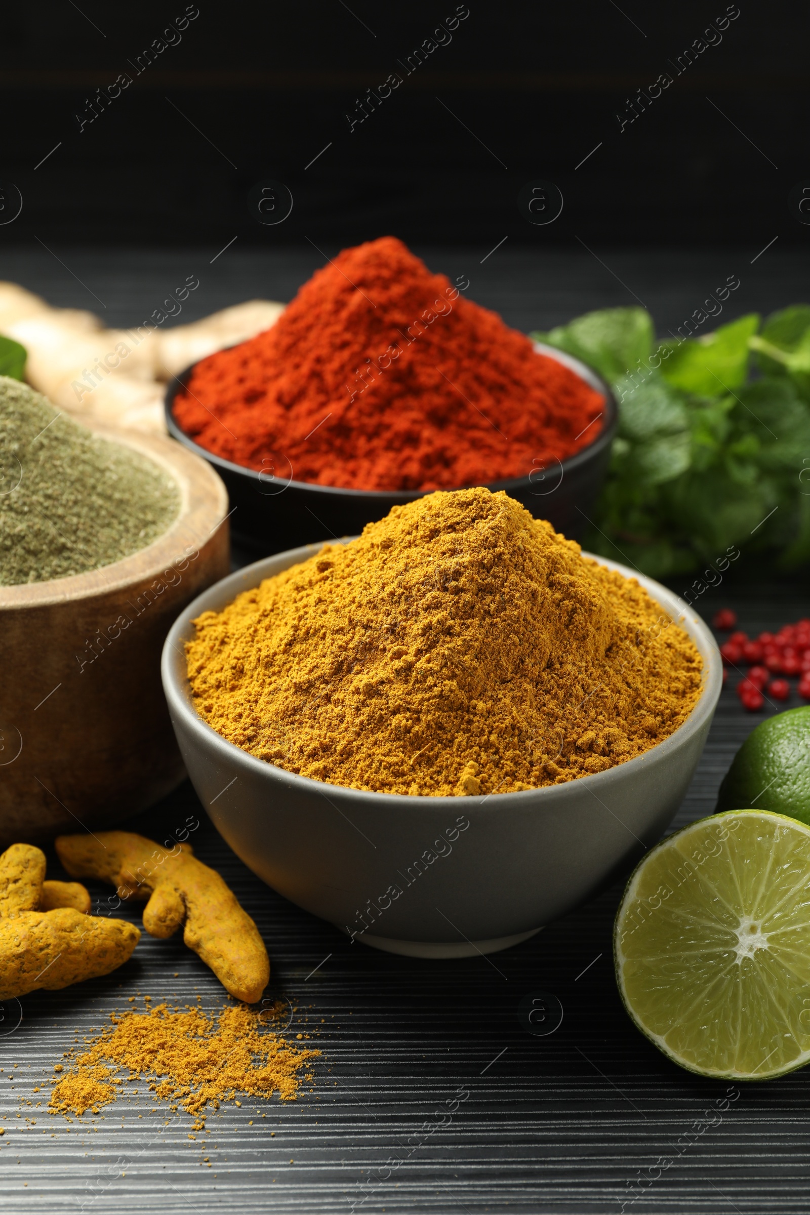 Photo of Different aromatic spices, lime and herbs on black background, closeup