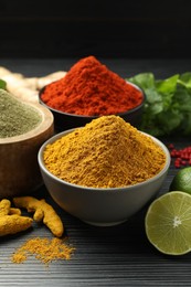 Photo of Different aromatic spices, lime and herbs on black background, closeup