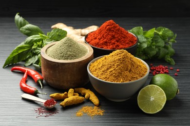 Photo of Different aromatic spices, lime and herbs on black background, closeup