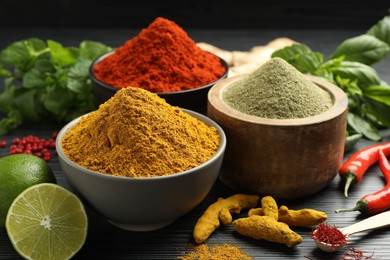 Photo of Different aromatic spices, lime and herbs on black background, closeup