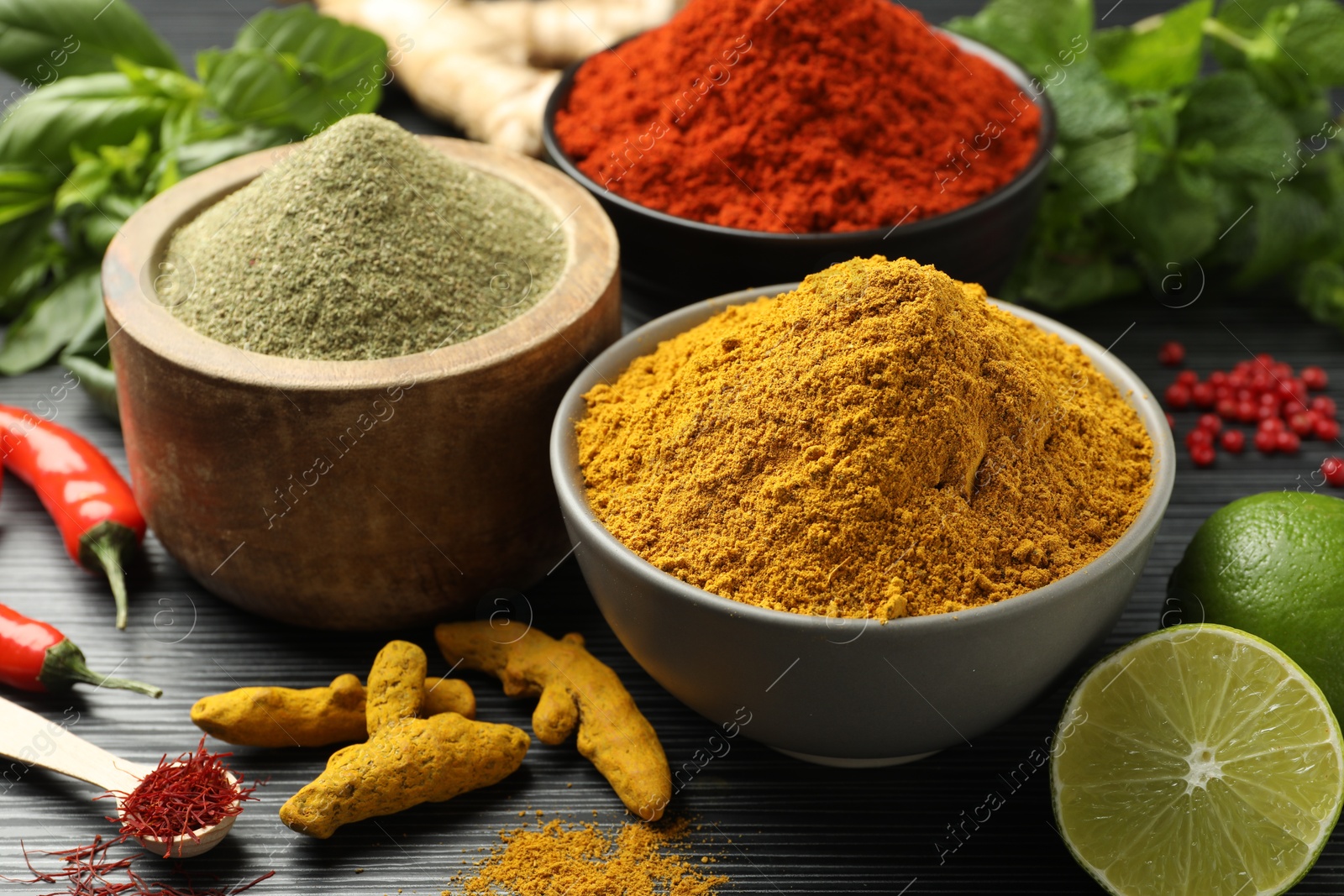 Photo of Different aromatic spices, lime and herbs on black background, closeup