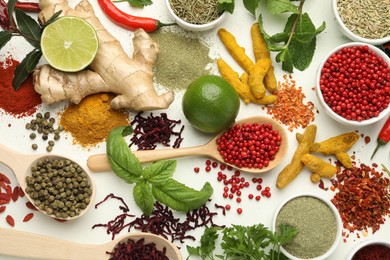 Different aromatic spices, lime and herbs on white background, flat lay