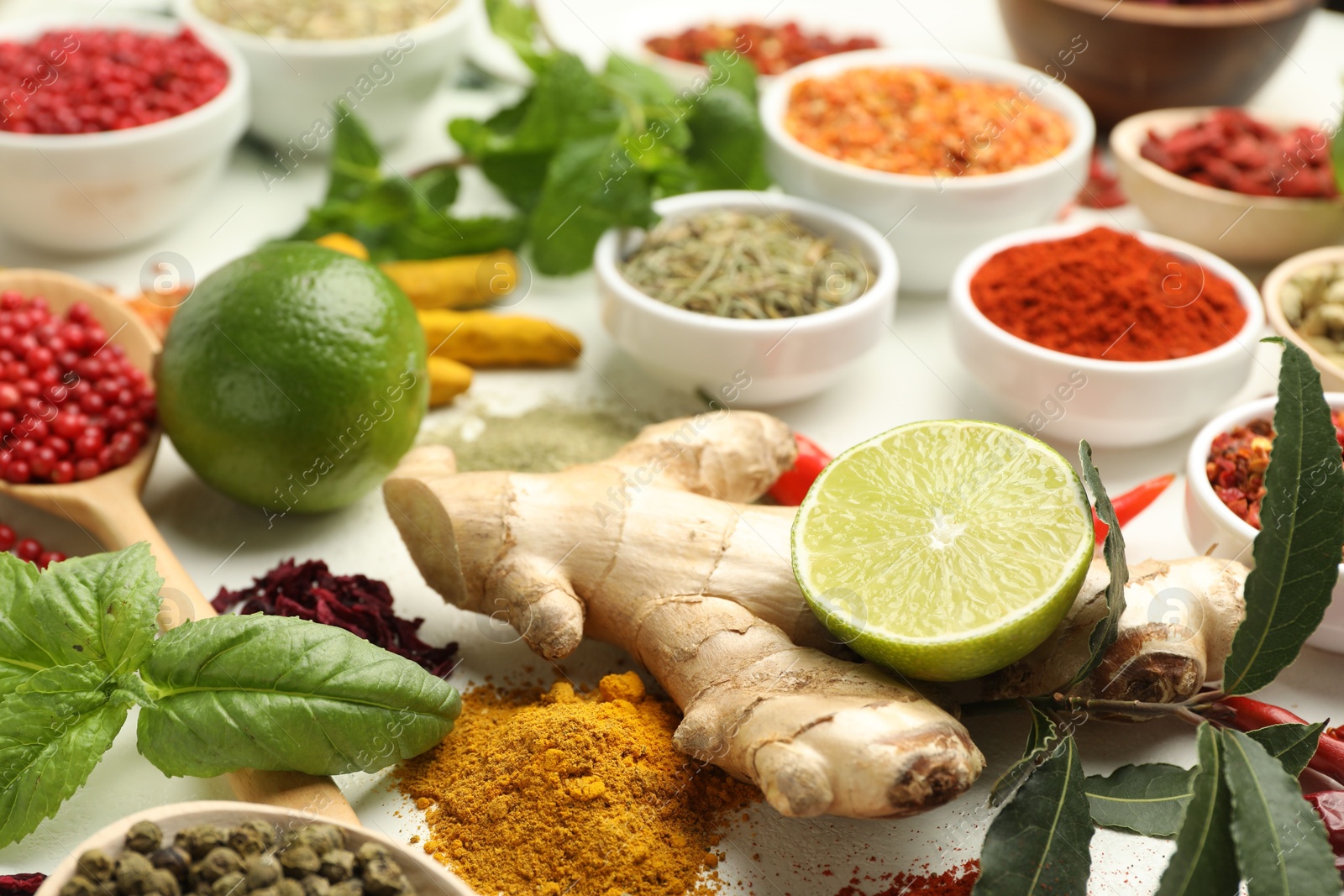 Photo of Different aromatic spices, lime and herbs on white background, closeup