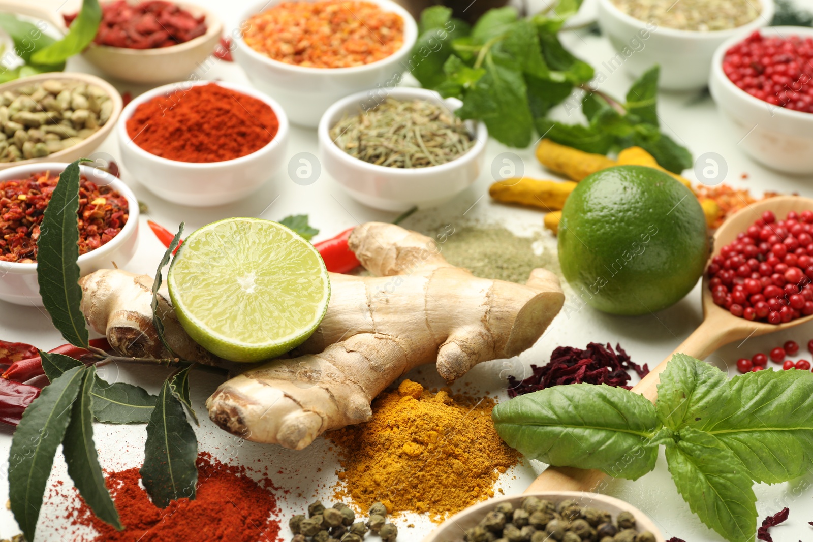 Photo of Different aromatic spices, lime and herbs on white background, closeup