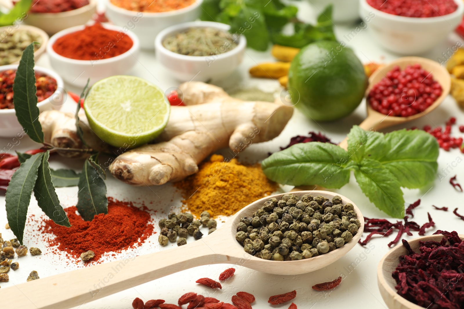 Photo of Different aromatic spices, lime and herbs on white background, closeup