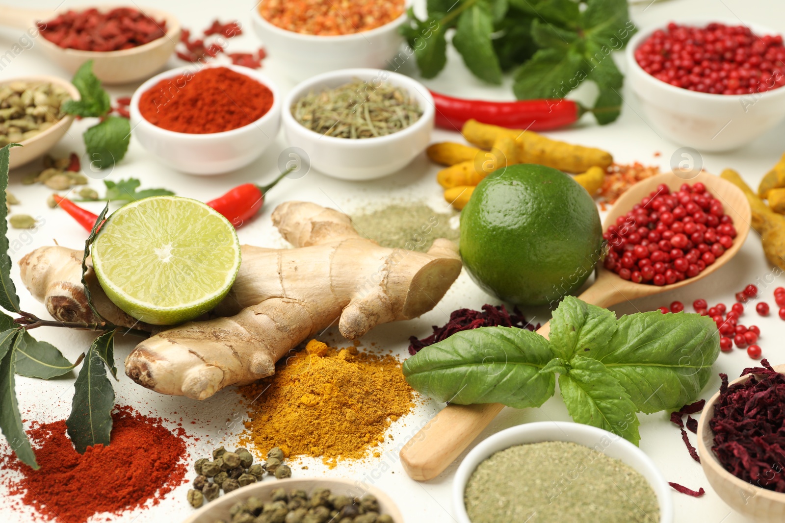 Photo of Different aromatic spices, lime and herbs on white background, closeup