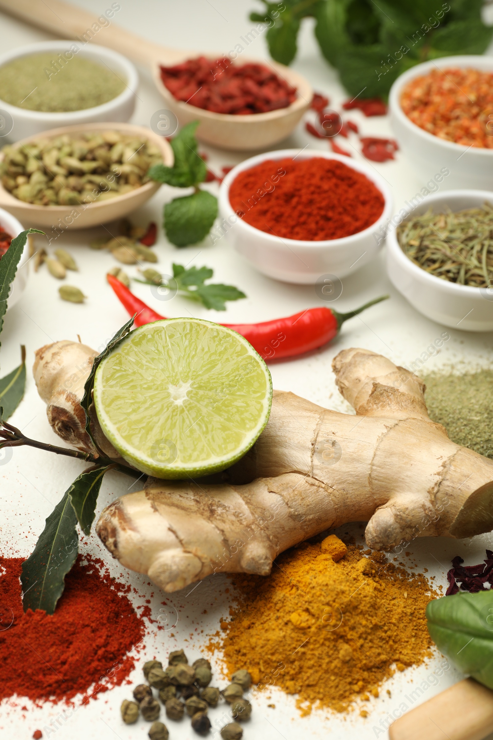 Photo of Different aromatic spices, lime and herbs on white background, closeup