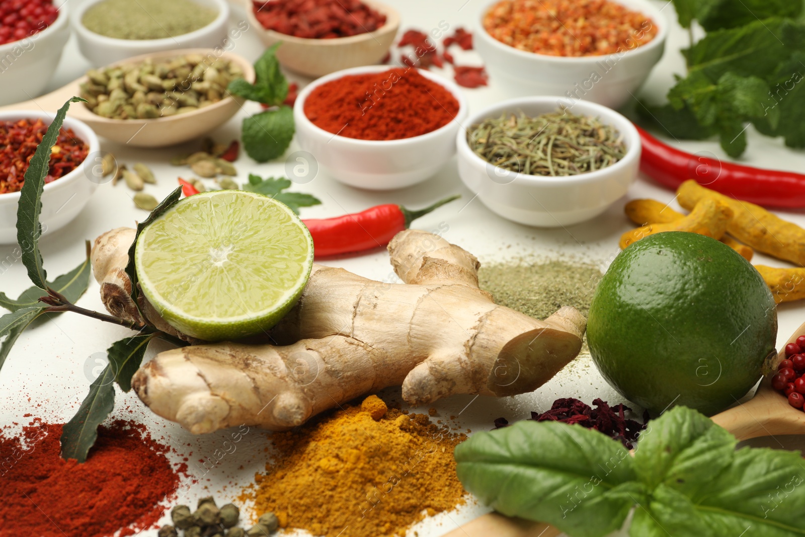 Photo of Different aromatic spices, lime and herbs on white background, closeup