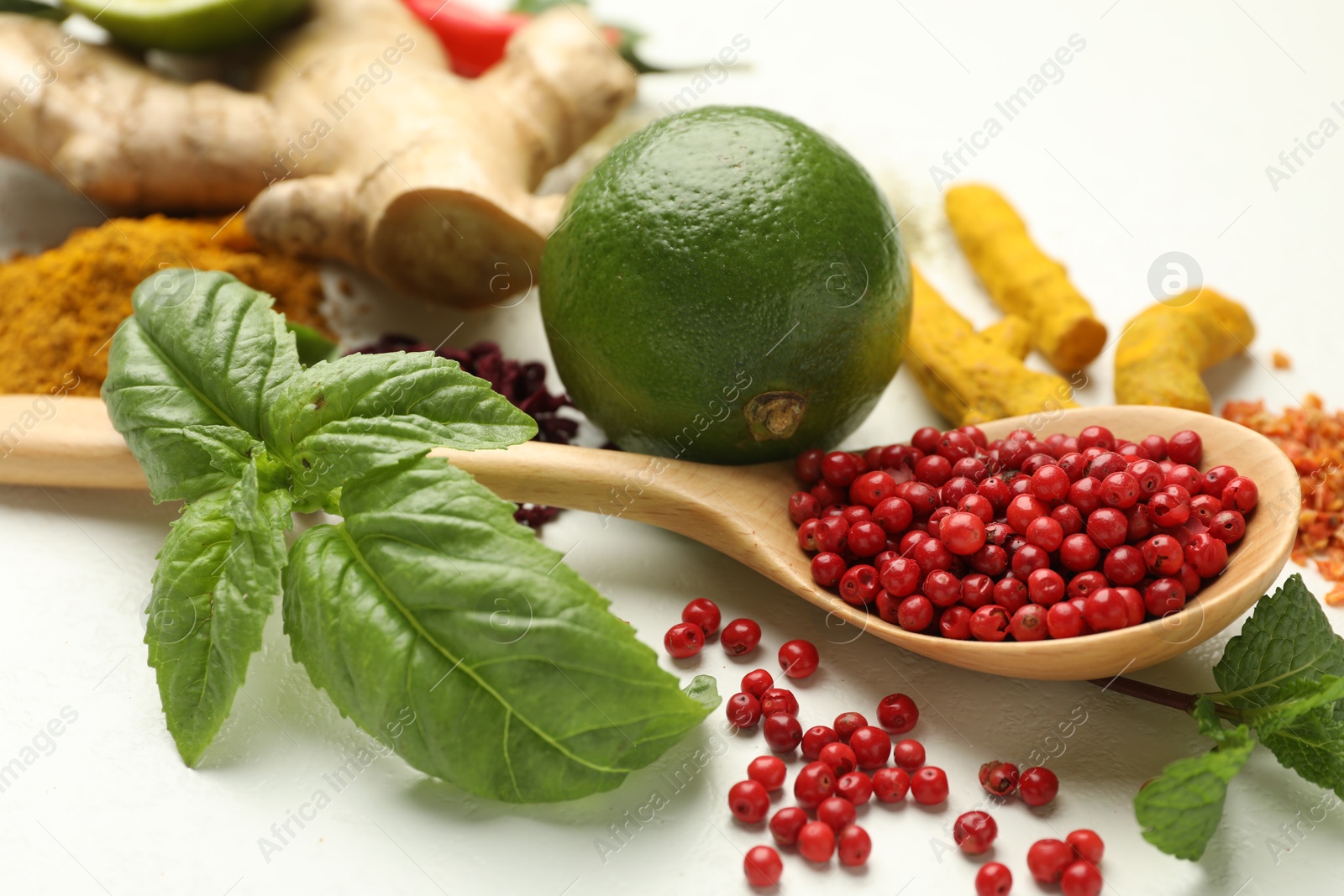 Photo of Different aromatic spices, lime and herbs on white background, closeup