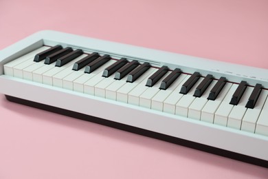 Photo of Synthesizer on pink background, closeup. Electronic musical instrument