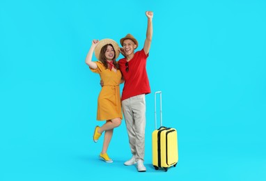 Photo of Happy travellers with suitcase on light blue background