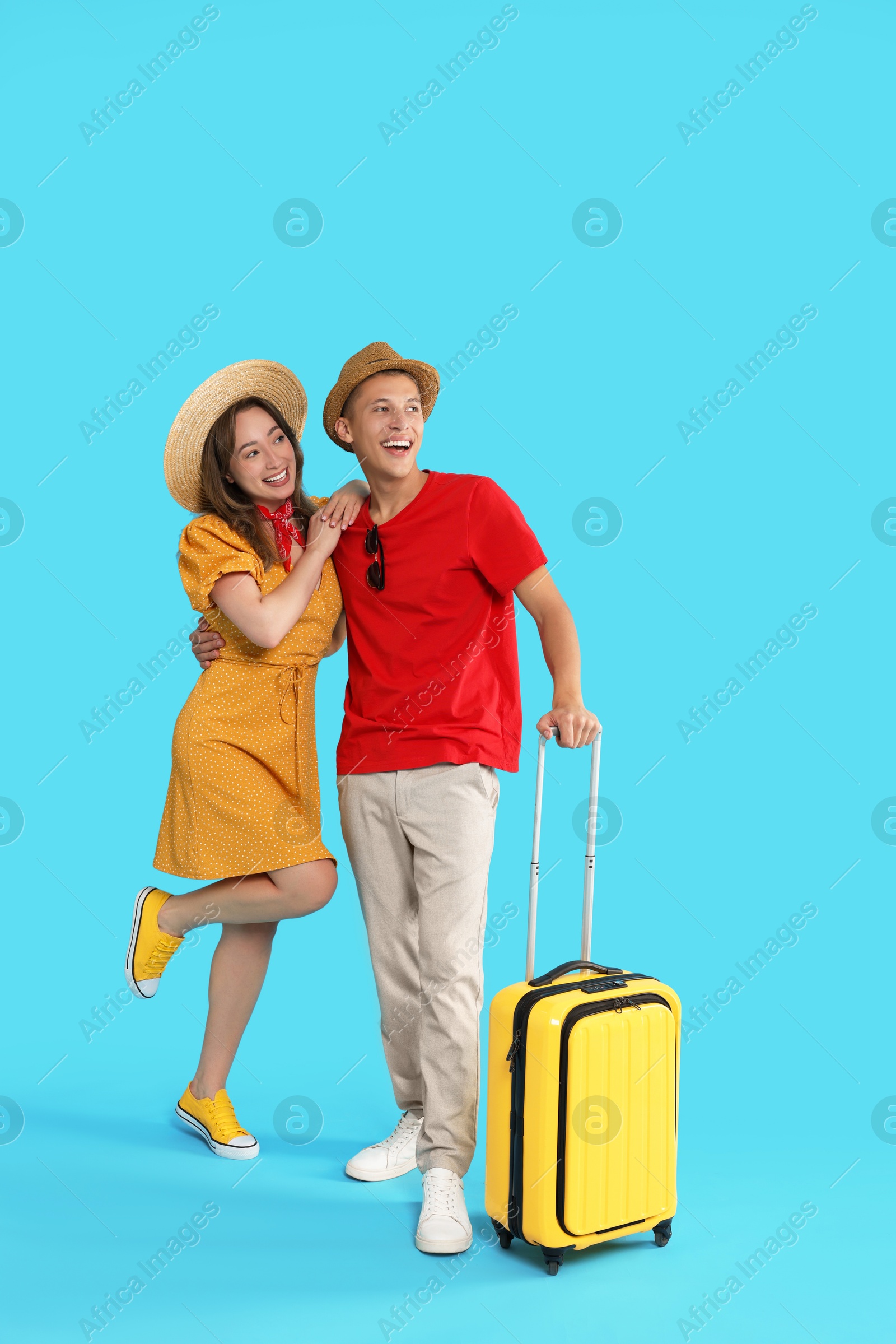 Photo of Happy travellers with suitcase on light blue background