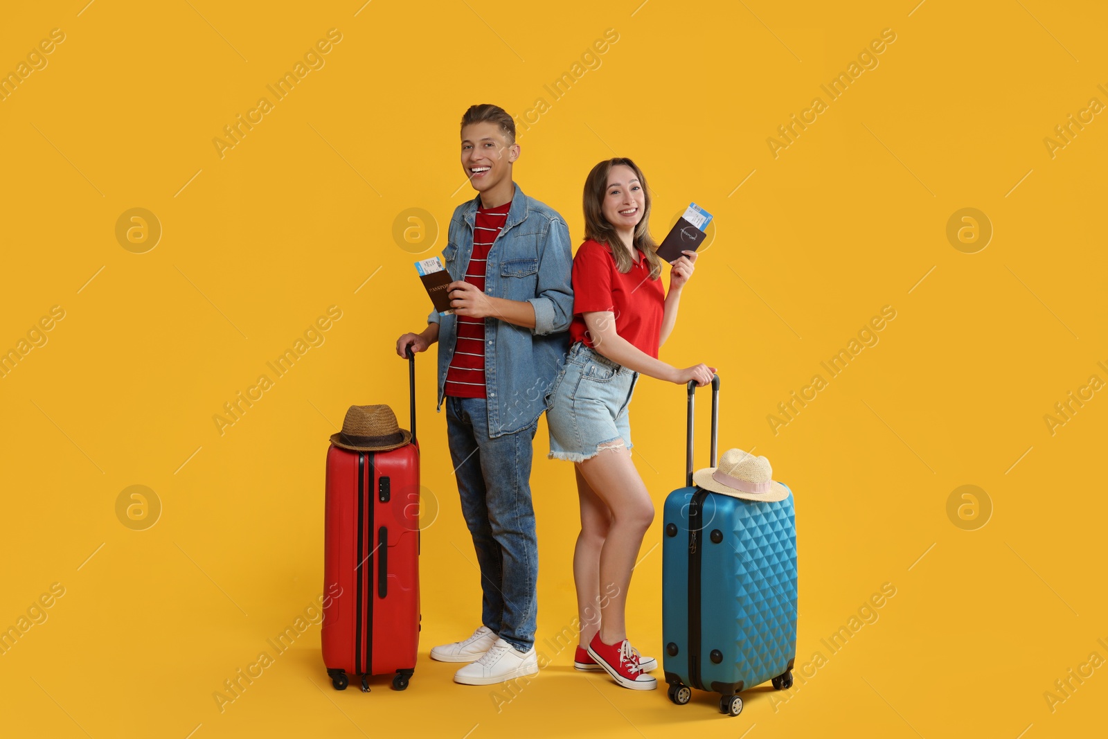 Photo of Happy travellers with suitcases, passports and tickets on yellow background