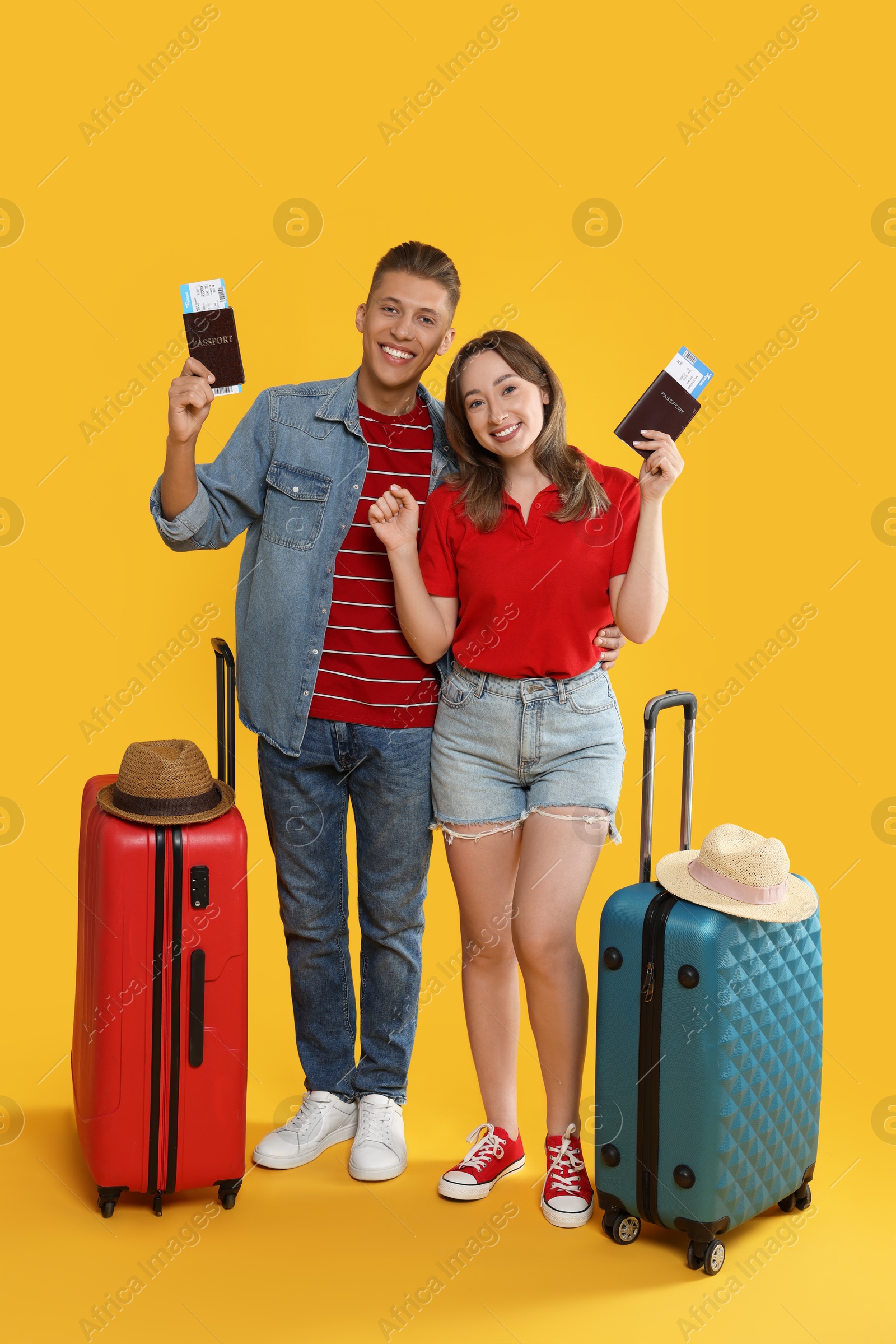 Photo of Happy travellers with passports, tickets and suitcases on yellow background