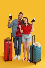 Photo of Happy travellers with passports, tickets and suitcases on yellow background