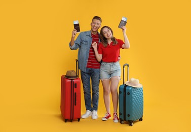 Photo of Happy travellers with passports, tickets and suitcases on yellow background