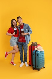 Photo of Happy travellers with passports, tickets and suitcases on yellow background