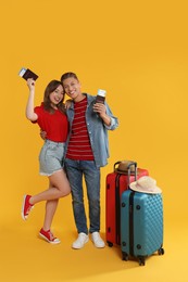 Photo of Happy travellers with passports, tickets and suitcases on yellow background