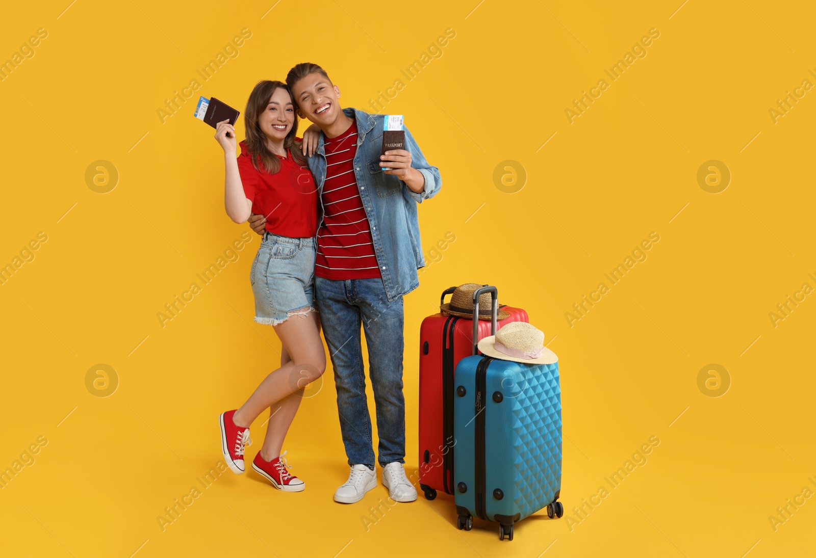 Photo of Happy travellers with passports, tickets and suitcases on yellow background