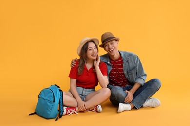 Photo of Happy travellers with backpack on yellow background